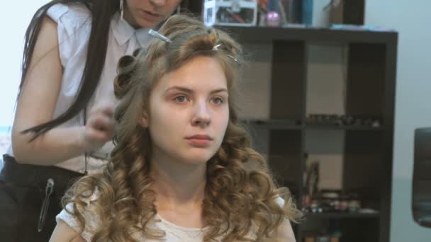 Мастер делает прическу девушке в салоне красоты — стоковое видео