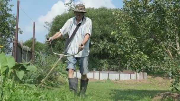 Ο εργαζόμενος κόβει το γρασίδι με string trimmer χορτοταπήτων — Αρχείο Βίντεο