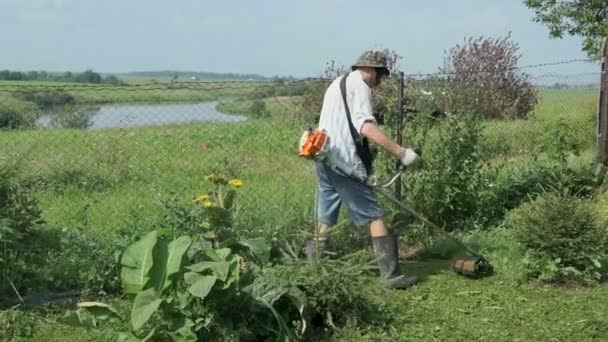 Werknemer snijdt het gras met een grasmaaier in de buitenlucht — Stockvideo