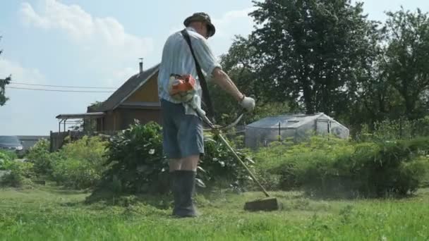 Homme taille herbe dans le jardin en utilisant tondeuse à gazon — Video