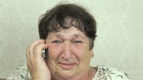 Old woman talking smartphone sitting on the sofa — Stock Video