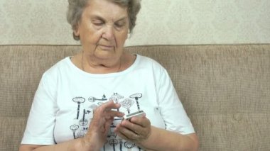 Bir cep telefonu evde tutan yaşlı kadın