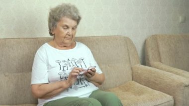 Bir cep telefonu evde tutan yaşlı kadın