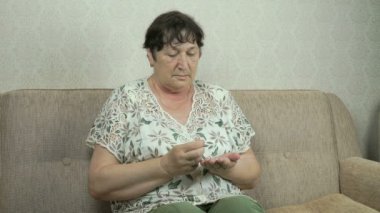 Yaşlı kadın hapları onun avuç içi inceliyor.