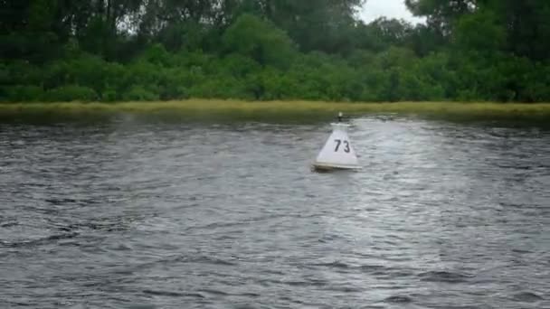 Witte boei drijvend in de rivier naast de kust — Stockvideo