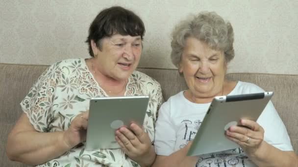 Twee oude vrouwen houden van de zilveren digitale tabletten — Stockvideo