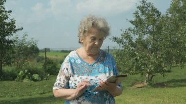 Dijital tablet açık havada tutan ederly kadın