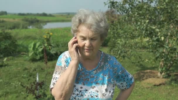 Alte Frau erzählt auf dem Smartphone im Freien — Stockvideo