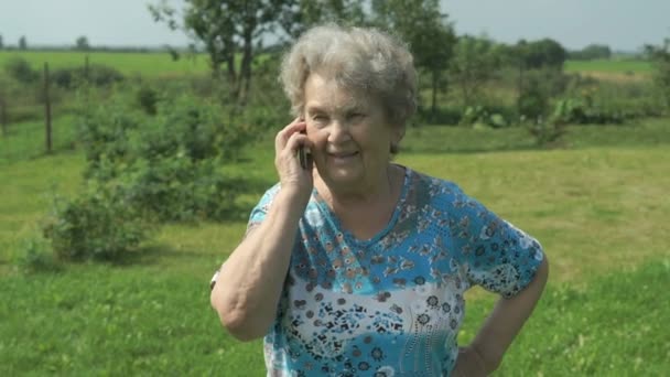 Old woman 80s telling on the smartphone outdoors — Stock Video