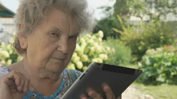 Femme âgée tenant une tablette numérique à l'extérieur — Video