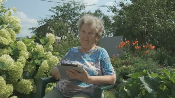 Elderly woman holding a digital tablet outdoors — Stock Video