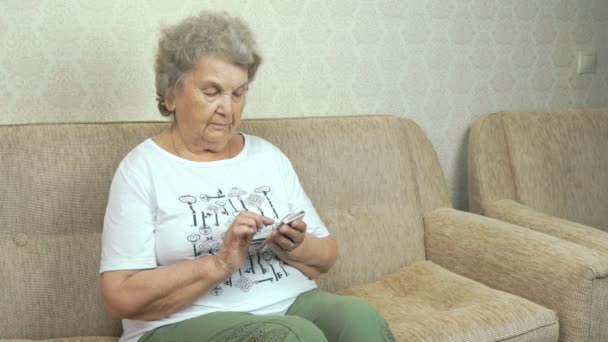 Velha avó segurando um telefone celular em casa — Vídeo de Stock