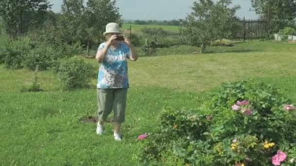 Літня жінка фотографує природу парку — стокове відео