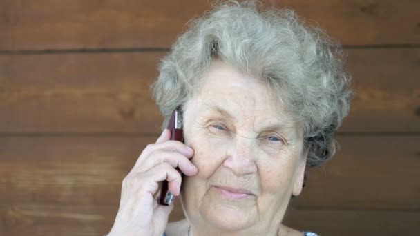 高齢者の女性が携帯電話で話しています。 — ストック動画