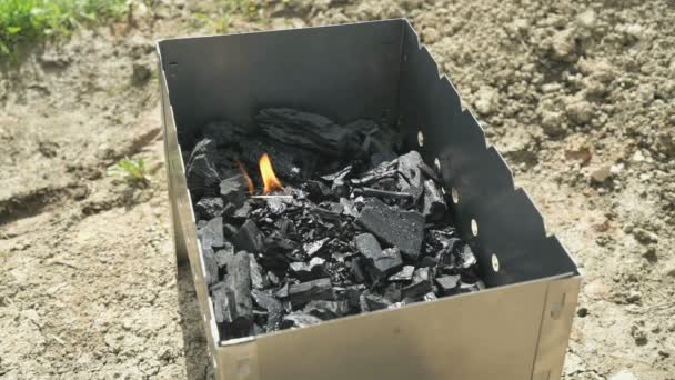La main avec une allumette allumée enflamme le charbon de bois — Video