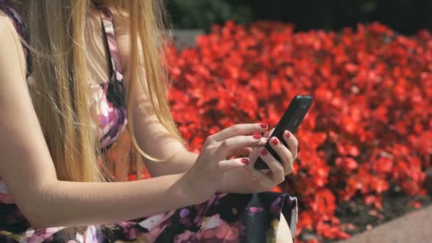 Jong meisje houdt van een mobiele telefoon en berichten leest — Stockvideo