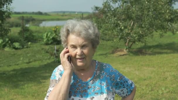 Elderly woman 80s communicates cell phone outdoors — Stock Video