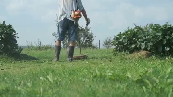 Cortacésped hombre corta la hierba al aire libre — Vídeos de Stock