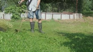 İşçi bir çim biçme makinesi kullanarak çim keser