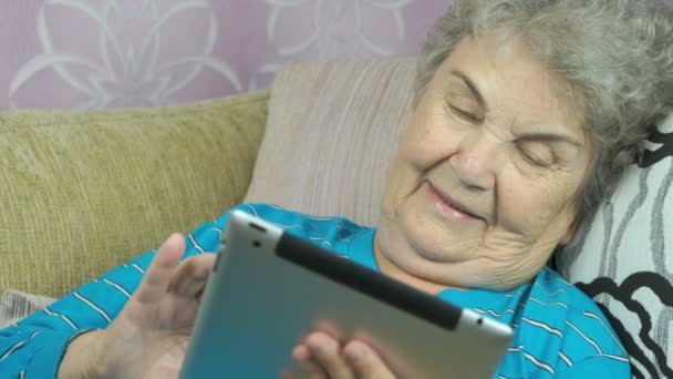 Mujer anciana sostiene una tableta en el interior — Vídeos de Stock