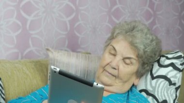 Üst düzey büyükanne bir tablet bilgisayar kapalı tutan