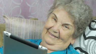 Yaşlı kadın bir tablet bilgisayar kapalı tutan