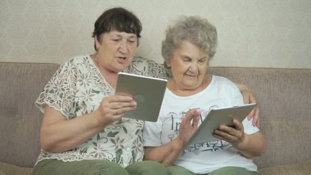Two elderly sisters holding silver digital tablets — Stock Video