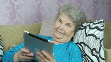 Yaşlı kadın bir tablet bilgisayar kapalı tutan