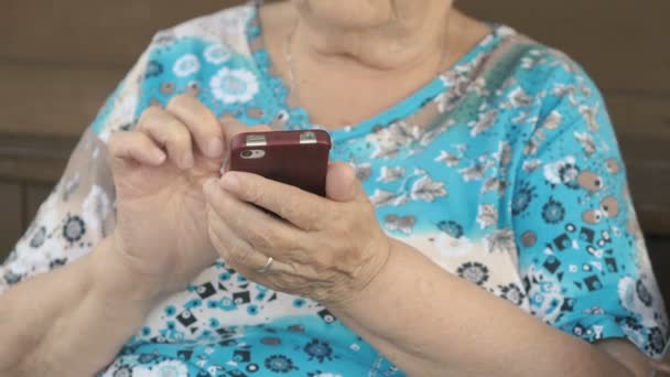 Alte Frau hält Smartphone in der Hand — Stockvideo