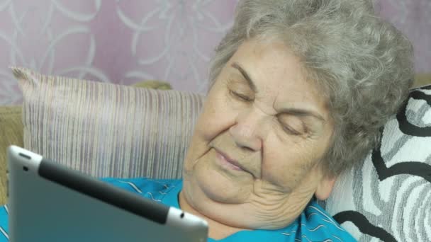 Старуха расслабляется за планшетным компьютером — стоковое видео