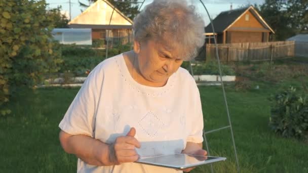 Yaşlı kadın bir dijital tablet açık havada tutan 80s — Stok video