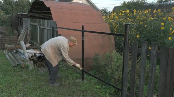 Старий 70-х років малює залізний паркан, використовуючи чорний — стокове відео