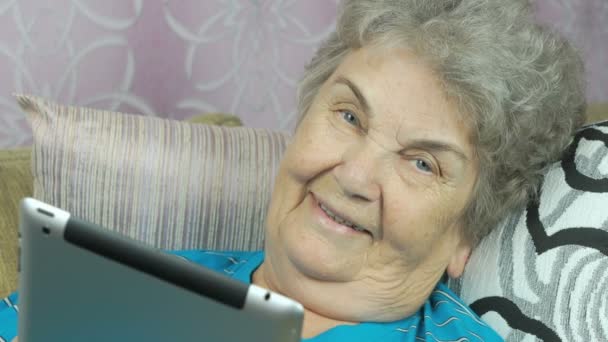 Sorridente donna anziana si trova sul divano della camera d'albergo — Video Stock