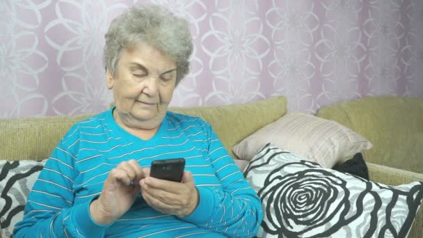 Yaşlı bayan bir cep telefonu kullanarak bir koltukta oturur — Stok video