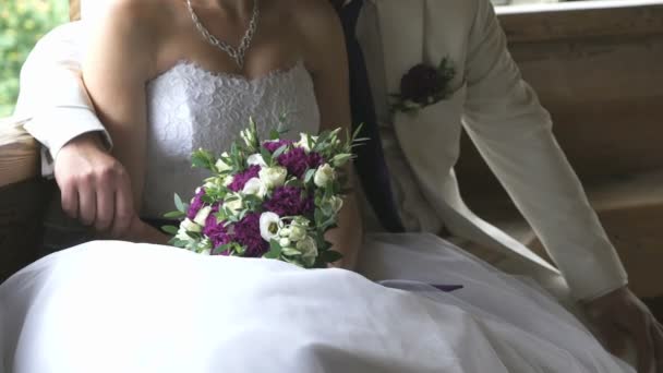 The bride and groom sitting and hugging on wooden — Stock Video