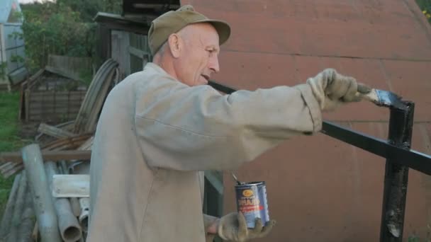 Werknemer het ijzeren hek met zwarte verf schilderen — Stockvideo