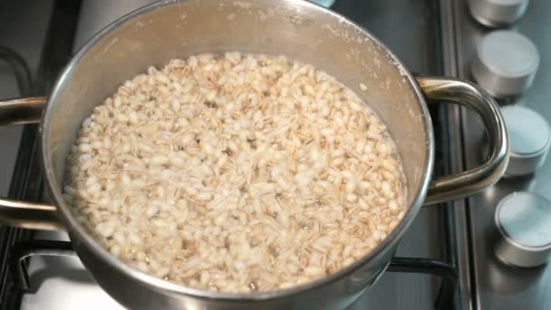 La sartén en el plato de cocina. Gachas de cebada cocidas en la sartén. El agua en la cacerola está hirviendo y burbujeando . — Vídeo de stock