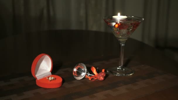 Burning candle in glass with precious stones. Engagement ring. — Stock video