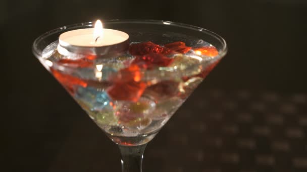 Burning candle in a glass scattered gemstones. Offer hands and hearts — Stock Video