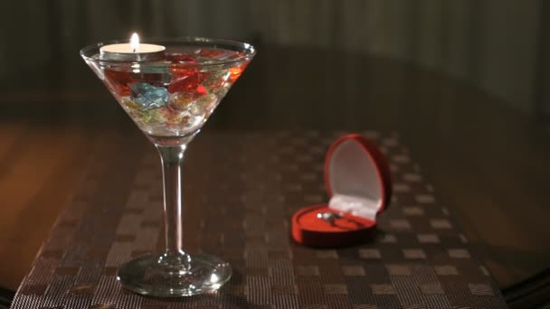Brinnande ljus i glas med ädla stenar. Förlovningsring. — Stockvideo