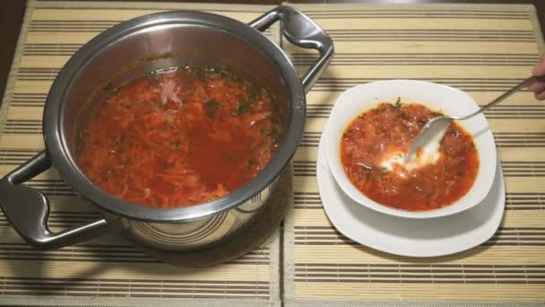 Cuchara crema agria se añade en plato blanco con sopa de remolacha — Vídeo de stock