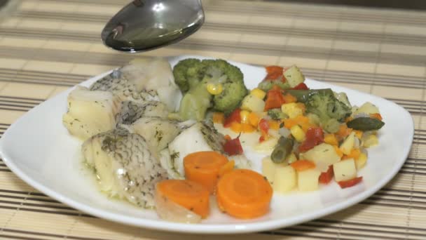 Macrourus ψάρι με λαχανικά στο λευκό πιάτο. Προσθήκη σπορέλαιο σε ένα τρόφιμο — Αρχείο Βίντεο