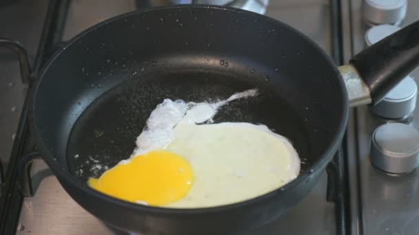Жареные яйца в сковороде. Сковородка стоит на плите. Крупный план — стоковое видео