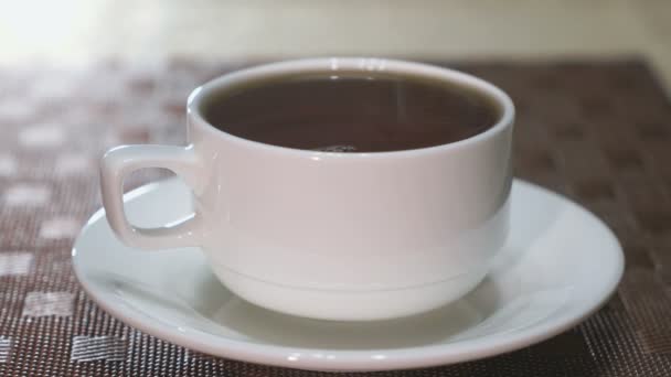 Porcelánový hrnek s černý čaj je na stole. Pára z hrnečku — Stock video