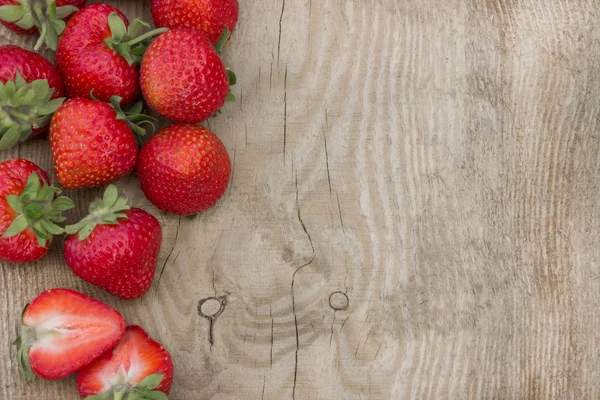 Verstreute Erdbeeren auf Holztisch (kann als Hintergrund verwendet werden, Karte) — Stockfoto