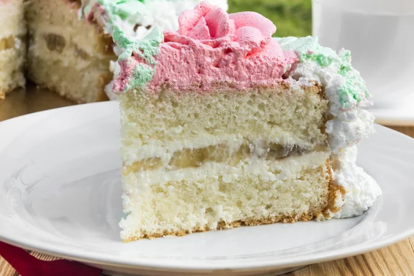 Pedazo de pastel de esponja con crema de cuajada y plátano, merengue crema decorada — Foto de Stock