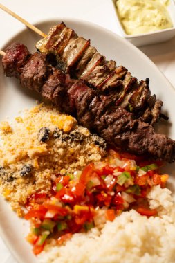 Makro yakın plan et şişi, pilav, farofa ve doğranmış biber ve soğan..