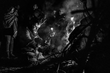 17 Şubat 2026 'da Portekiz' in Vila Boa de Ousilhao kentindeki Ortaçağ Karnavalı sırasında el oyması ahşap bir şeytan maskesi içinde maskeli bir şahıs, duman, ateş ve ayin alevleri arasında közlerin üzerinden atlıyor..