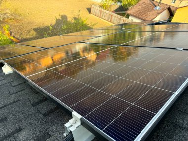 Güneş panellerini barındıran, güneş ışığını emen, evler için temiz ve sürdürülebilir enerji sağlayan bir çatı manzarası.