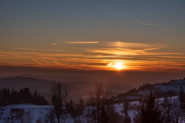 Sunset with colorful sky from Koczy Zamek hill above Koniakow village in winter Beskid Slaski mountains in Poland